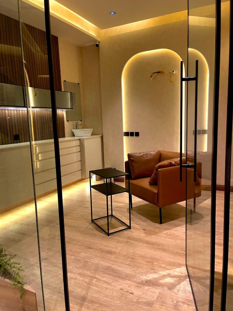 A backlit arched reception lounge with warm timber flooring and leather seating, part of a healthcare interior fit-out by ZM Architects.
