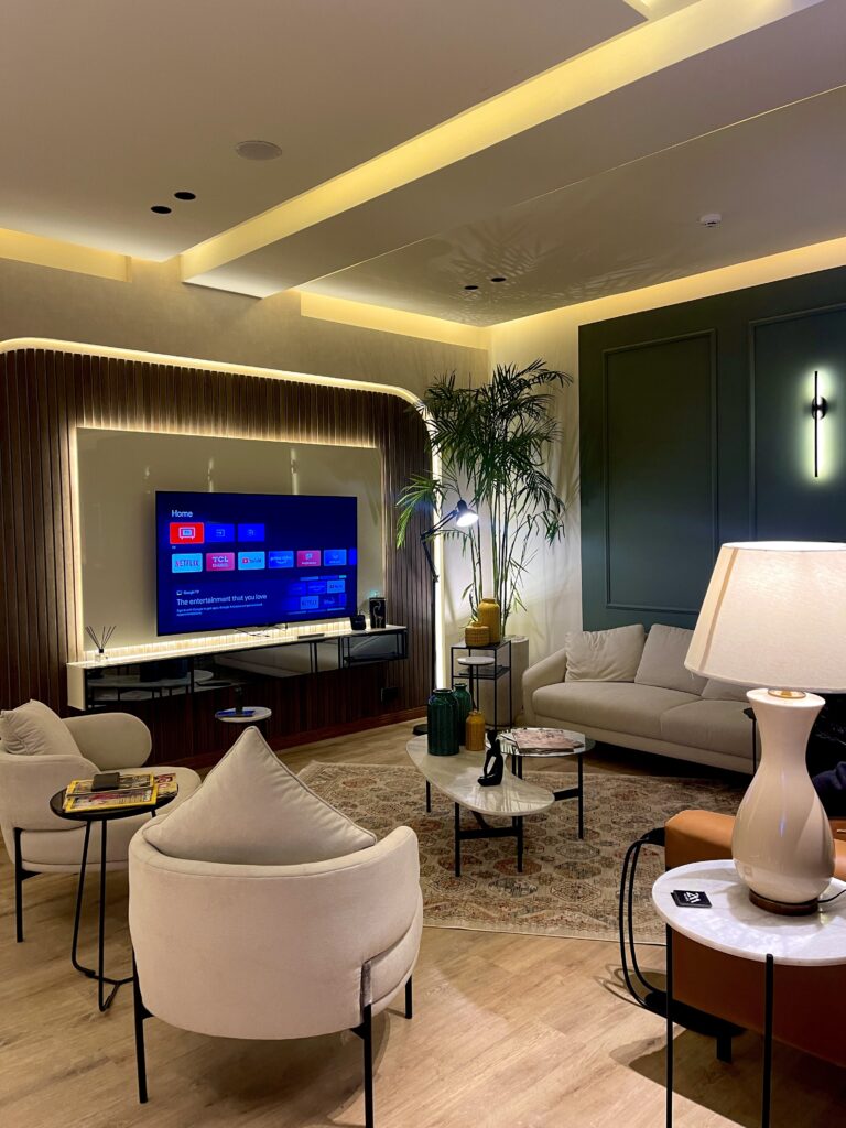 A contemporary lounge interior with layered seating, backlit paneling, and a media wall, designed by ZM Architects for a commercial hospitality space.