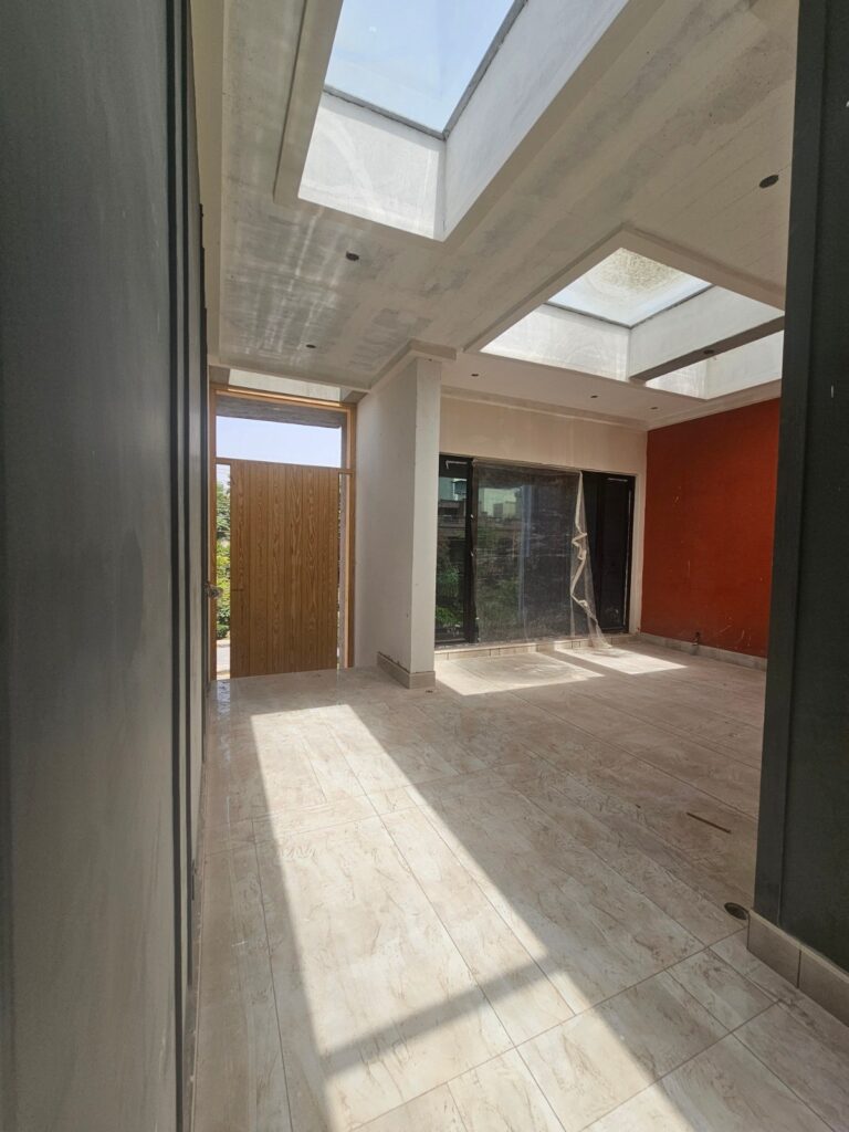 A light-filled residential hallway in Lahore with a linear skylight and warm timber flooring, designed by ZM Architects.
