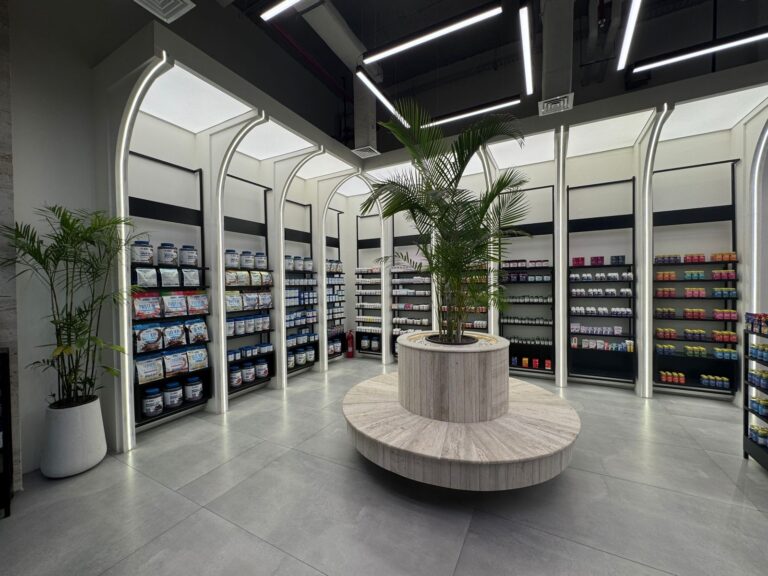 The completed interior of "My Drug Store" pharmacy in Lahore, featuring arched display shelving around a central planted seating column. Designed by ZM Architects.