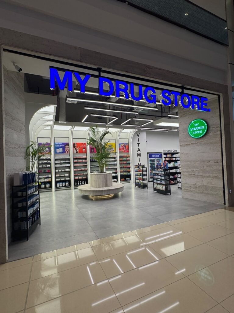 The illuminated storefront entrance of "My Drug Store" pharmacy in Lahore, designed by ZM Architects with backlit signage and arched interior sightlines.