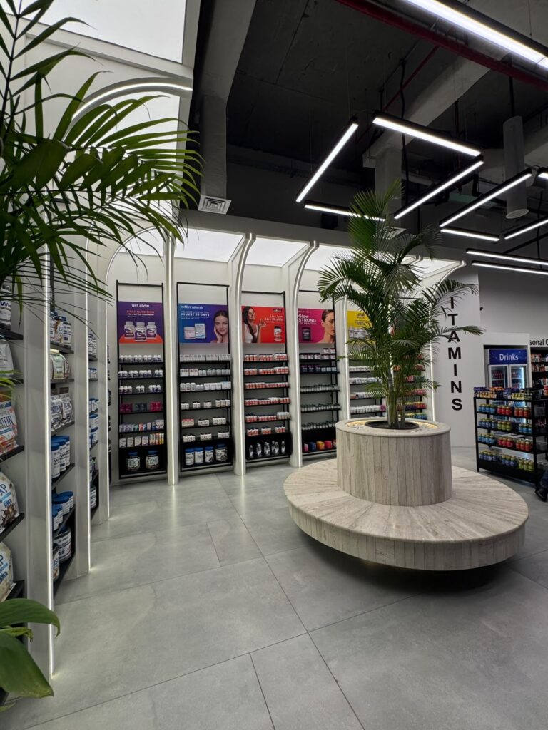 Arched retail shelving surrounding a planted display column within "My Drug Store" pharmacy in Lahore, designed by ZM Architects.