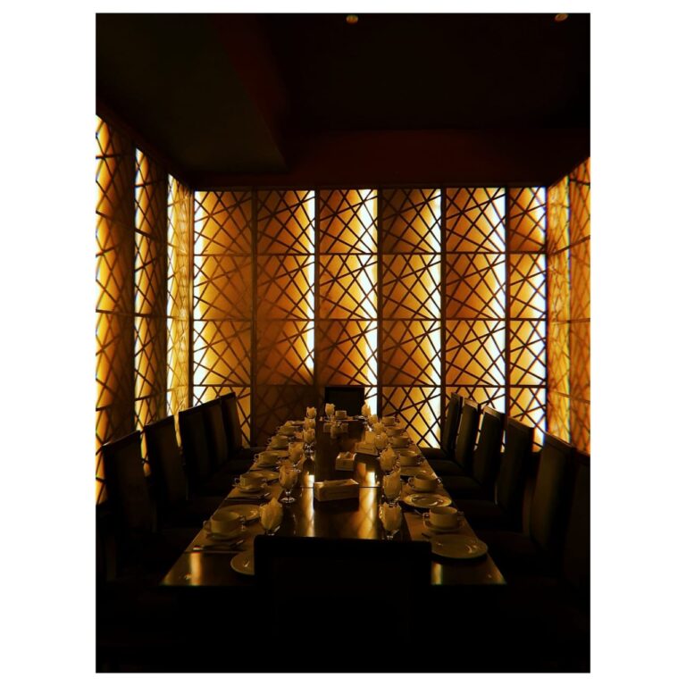 A private dining room enclosed by woven rattan screen panels and a long communal table, designed by ZM Architects.