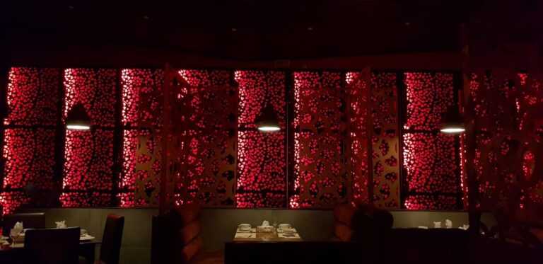A restaurant dining room enclosed by red perforated metal panels, designed by ZM Architects.