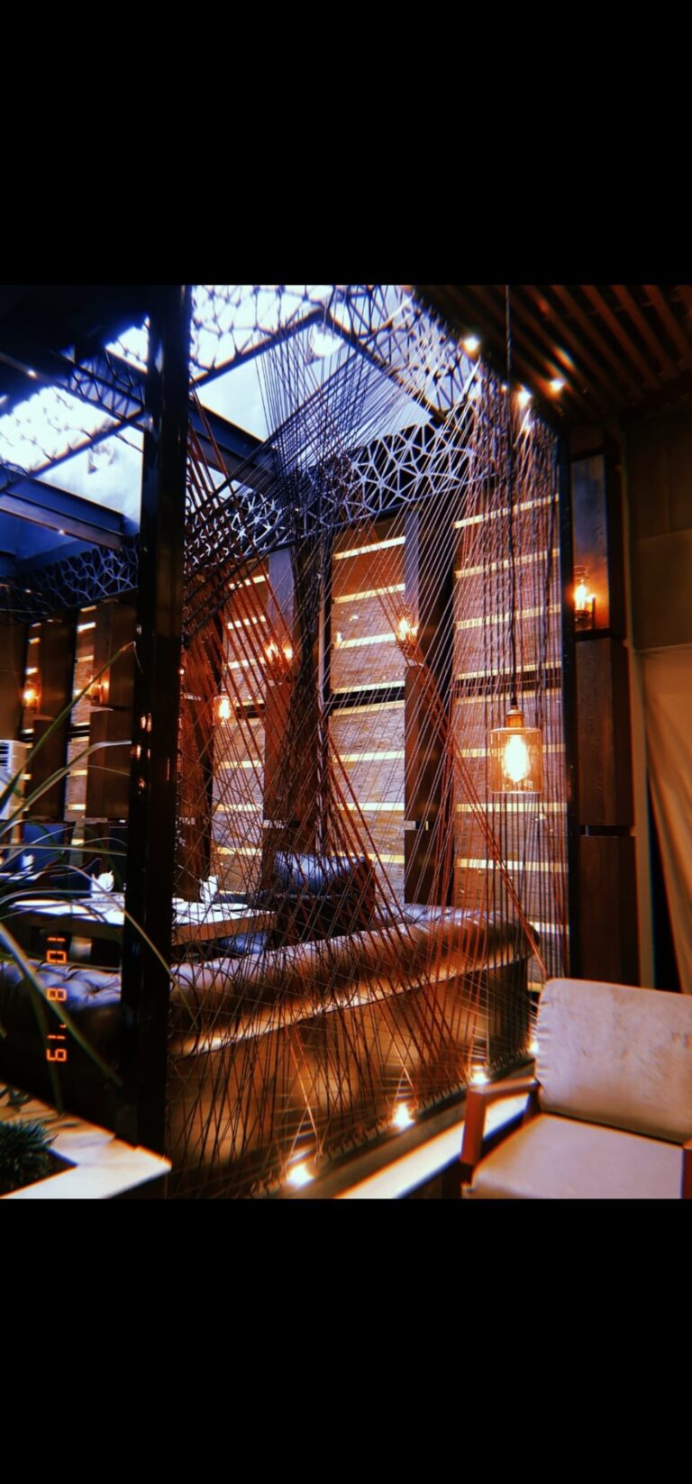 An intimate restaurant seating nook framed by a geometric wood screen and ambient lighting, designed by ZM Architects.